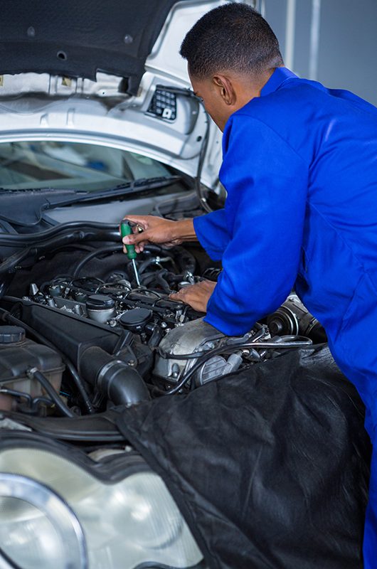 Attentive mechanic servicing automobile car engine in repair garage